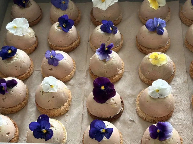 Gros plan sur des bouchées en forme de dôme garnies de fleurs violettes et blanches.