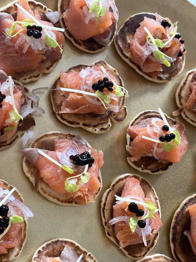 Petites bouchées rondes au saumon, avec des pousses fraîches et une fine garniture claire.